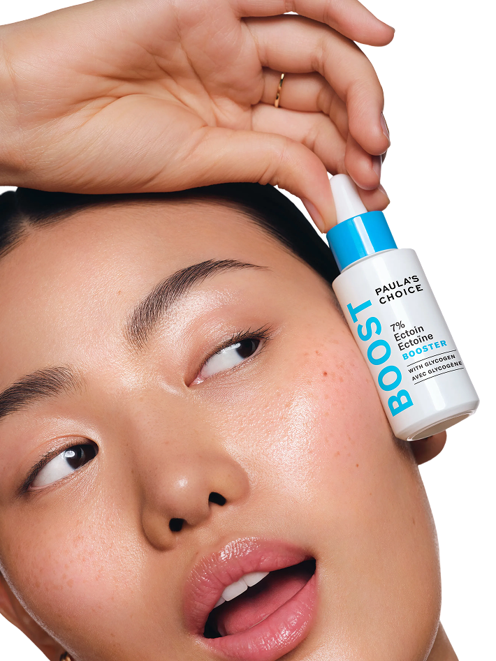 Person holding a bottle of Paula's Choice skincare product near their face.
